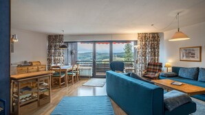A living room with a sofa, coffee table, and dining area. - Apartment 'Terrassenpark 160' with Mountain View, Balcony and Wi-Fi (Schonach)