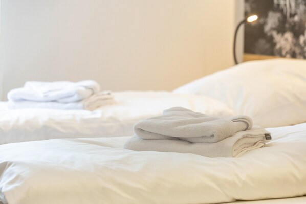 A hotel room with two beds, each with neatly folded white towels.
