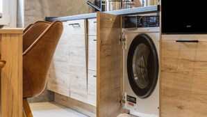 Une cuisine moderne avec des meubles en bois, un lave-linge encastré et une chaise marron.