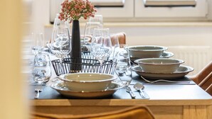 Une table à manger dressée avec des assiettes, des bols, des verres et des couverts, et un vase de fleurs placé au centre.