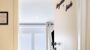 L’entrée d’une chambre d’hôtel, avec une porte, un menu encadré accroché au mur et une enseigne portant le nom de l’hôtel.