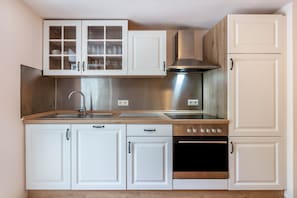 Une cuisine avec des armoires blanches, une hotte de cuisinière en acier inoxydable, un four double et un évier.