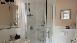 Une salle de bain moderne avec une douche à parois de verre, un lavabo avec un miroir et des toilettes.