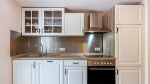 Una cocina con armarios blancos, una campana extractora de acero inoxidable, un horno doble y un lavamanos.