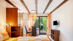 A bedroom with a bed, a desk, a chair, a TV, and a sliding door to a balcony. - Apartment '1' with Private Terrace, Garden and Wi-Fi (Bad Bellingen)