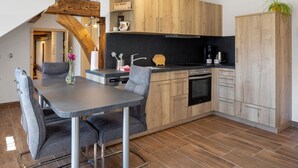 Eine moderne Küche mit Holzschränken, einem Esstisch mit Stühlen und einer schwarzen Arbeitsplatte.
