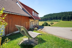 Une maison avec un toit en pente, une clôture en bois et un banc à l’extérieur.