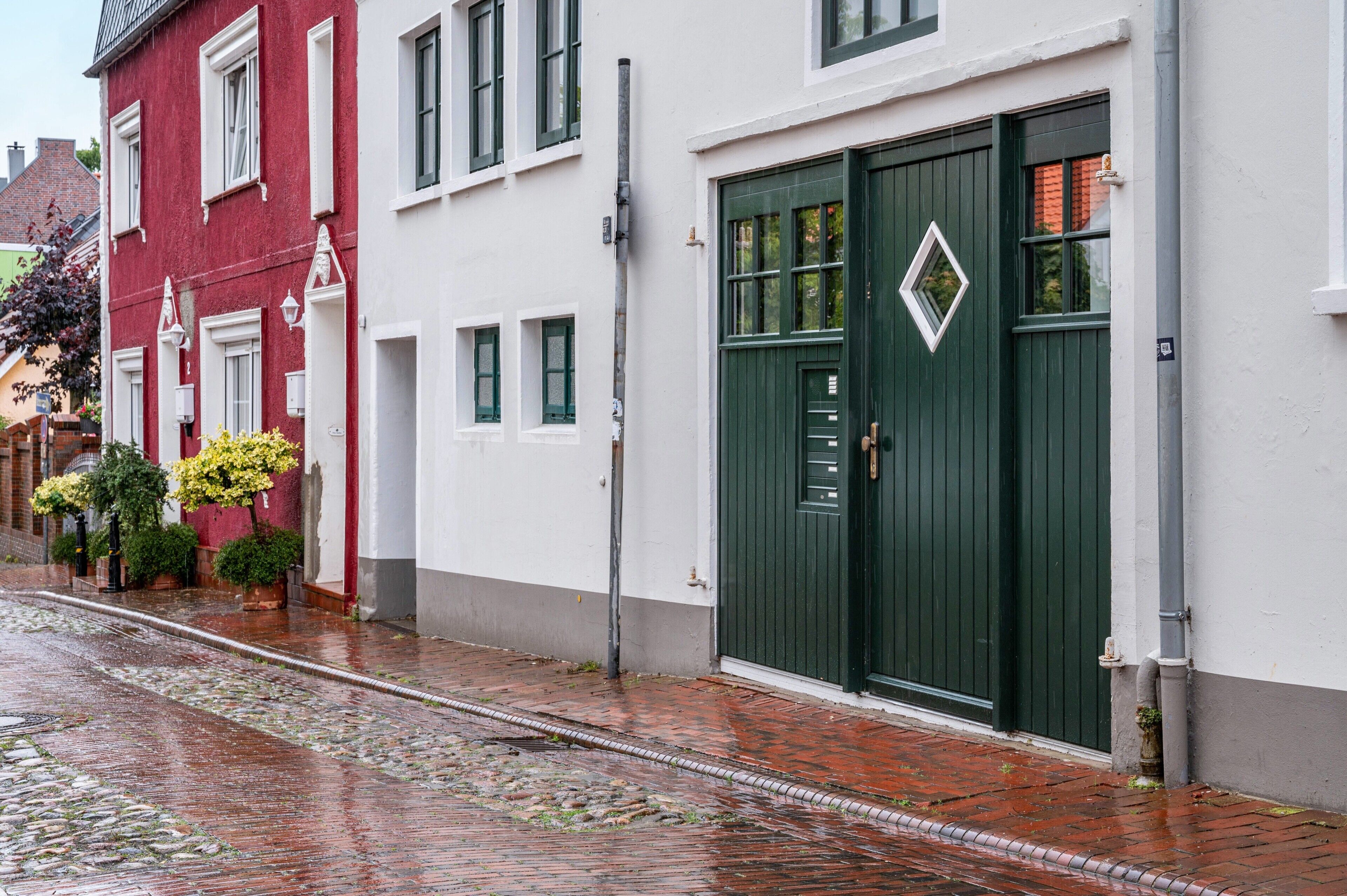 Eine Straße mit Gebäuden, einem Kopfsteinpflasterweg und einer grünen Tür.