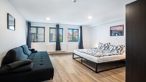 A modern bedroom with a bed, a sofa, and a window with curtains. - Modern apartment in the city center of Jever (Jever)