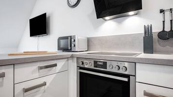 Een moderne keuken met een inbouwoven, een magnetron en een spoelbak.