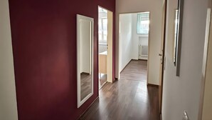Een gang met een rode wand, houten vloer en witte deuren.