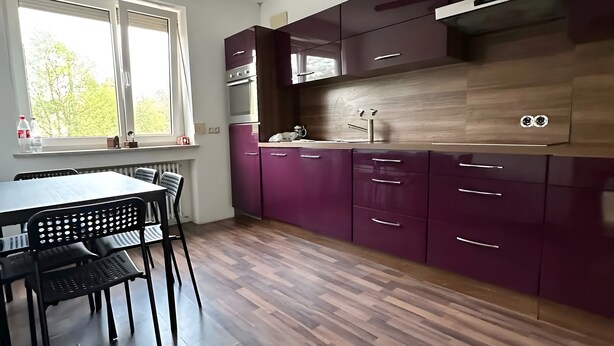 Een moderne keuken met houten vloeren, een eettafel met stoelen en een plafondventilator.