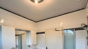 Een moderne badkamer met een wit wastafel, spiegel en douche.