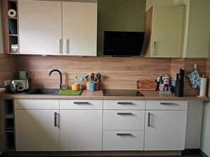 A modern kitchen with a built-in microwave, a sink, and a wooden countertop. - Apartment 'Wohlfühlen Und Mehr' with Balcony and Wi-Fi (Rastatt)