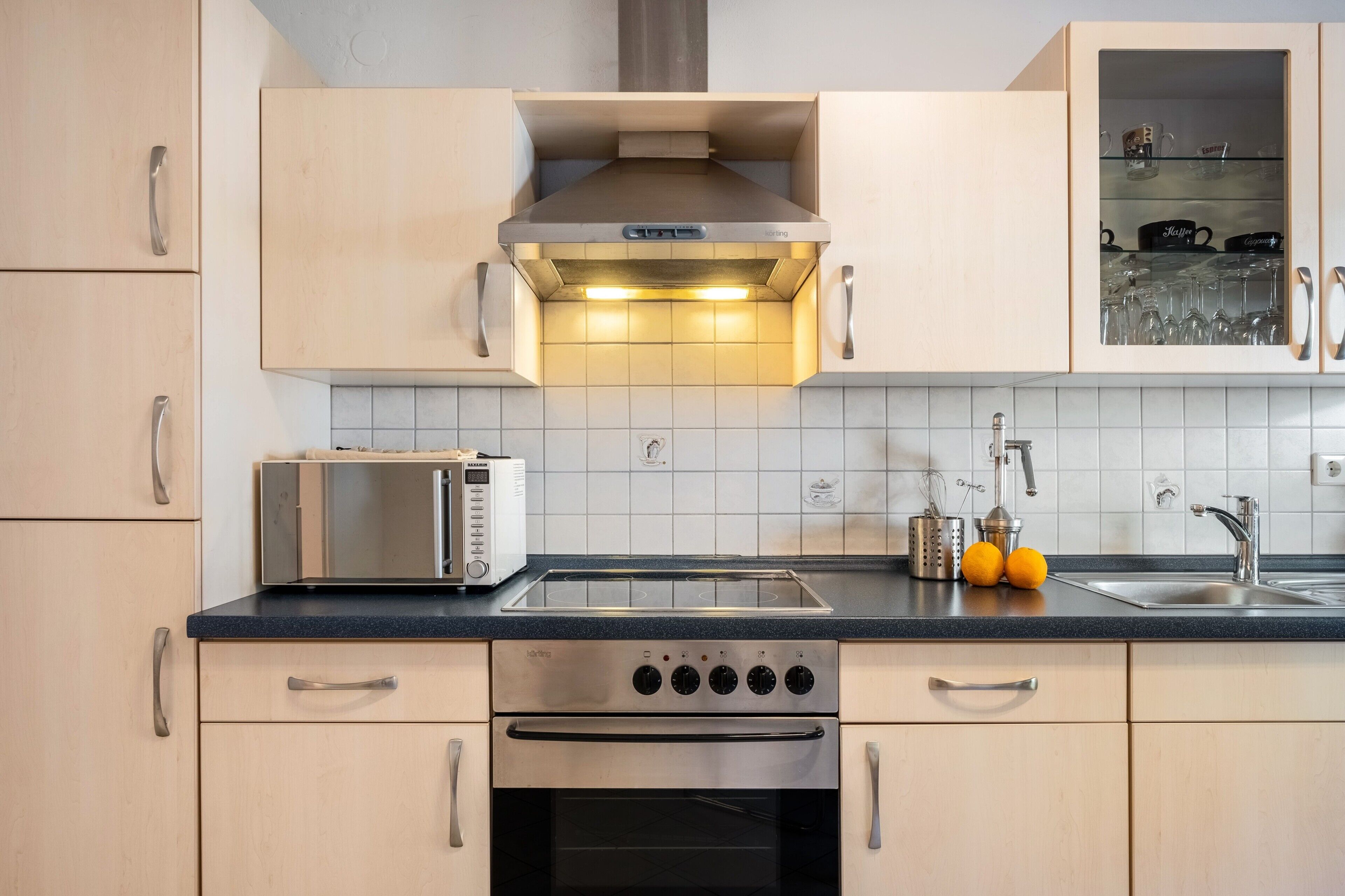 Una cocina moderna con tostadora integrada, estufa de acero inoxidable y un lavamanos doble.