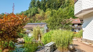 A residential area with a pond, garden, and a house with solar panels. - Apartment 'Ferienwohnung Uli Schätzle' with Mountain View, Private Terrace and Wi-Fi (Hornberg)
