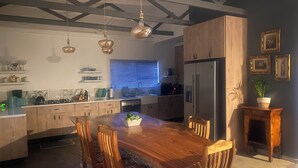 A modern kitchen with a wooden dining table, chairs, and pendant lights. - Peaceful escape in the coast of Paradise beach, Jeffreys Bay, South Africa (Jeffreys Bay)