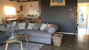A modern living room with a grey sofa, patterned cushions, a glass coffee table, and a wicker basket. - Peaceful escape in the coast of Paradise beach, Jeffreys Bay, South Africa (Jeffreys Bay)