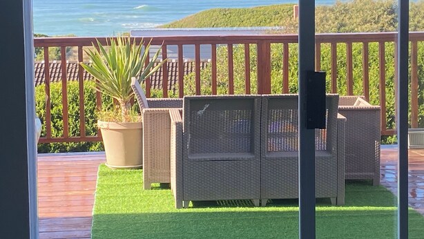A balcony with wicker furniture, a potted plant, and a view of the ocean. - Peaceful escape in the coast of Paradise beach, Jeffreys Bay, South Africa (Jeffreys Bay)