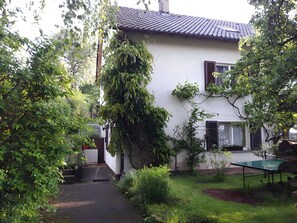 Una casa amb teulada de rajola, un jardí amb taula i un camí que porta a l'entrada.