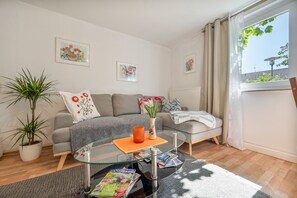Un salon moderne avec un canapé gris, une table basse en verre et une plante en pot.