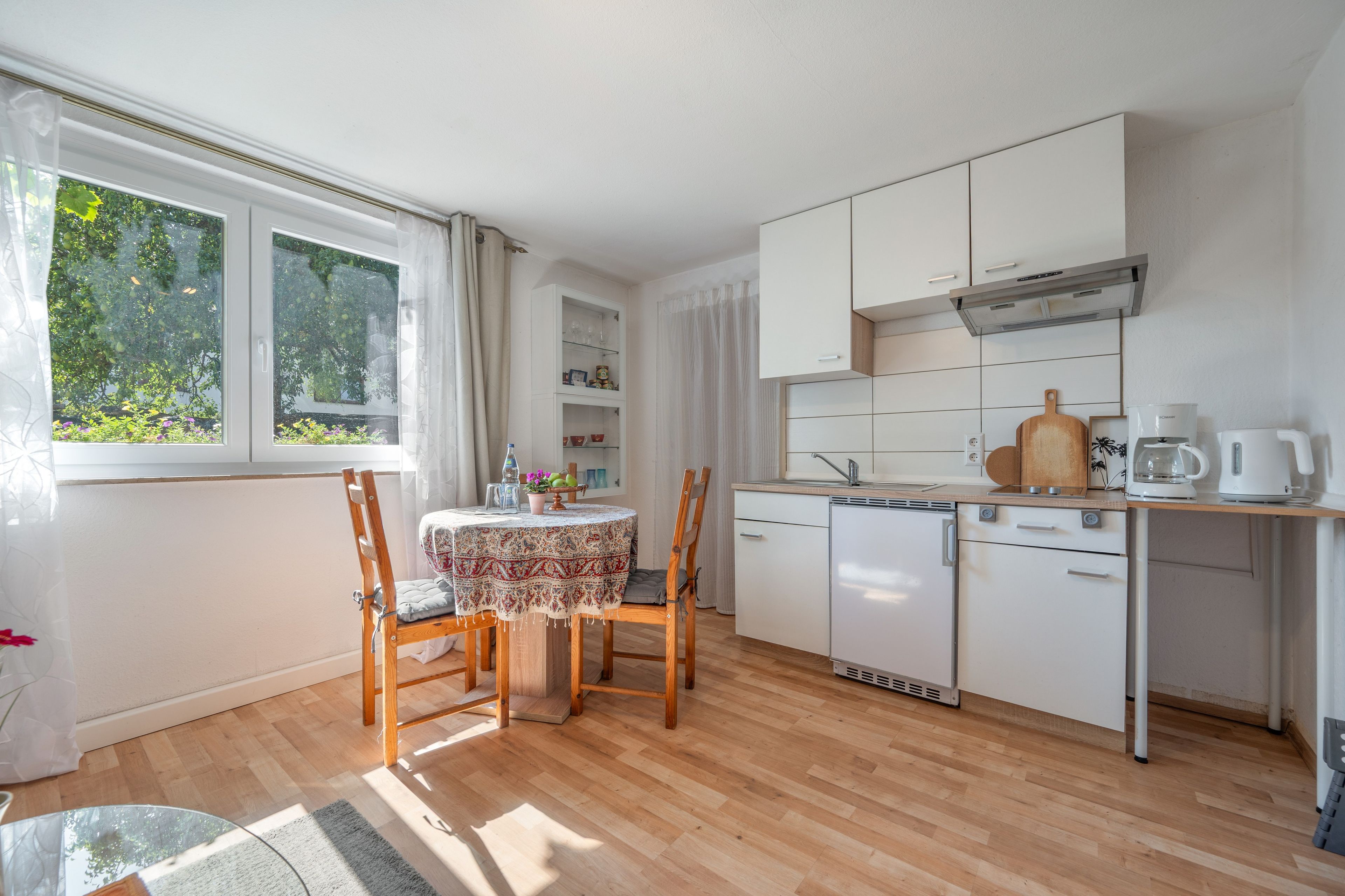 A compact kitchen with a dining area, featuring a built-in oven, a sink, and a coffee maker.
