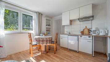 A compact kitchen with a dining area, featuring a built-in oven, a sink, and a coffee maker.