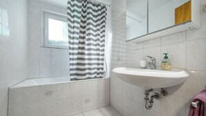 A bathroom with a bathtub, a sink, and a window. - Apartment 'Haus Zur Bienenweide' with Shared Terrace, Balcony and Wi-Fi (Schömberg)
