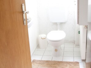 Un baño con inodoro, lavamanos y pared blanca.