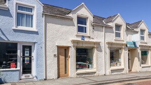 A row of buildings with a medical hall sign, a pharmacy, and a convenience store. - Medical Hall (Cemaes Bay)