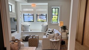 Ein geräumiges Wohnzimmer mit großem Fenster, einer Couch, einem Couchtisch und einer Lampe.