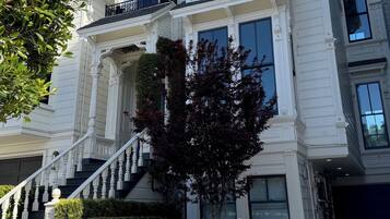 A multi-story building with a grand entrance, a staircase, and a well-maintained garden.