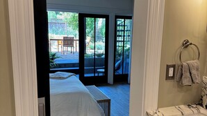 Ein Schlafzimmer mit einem großen Bett, einer Holzbank und Blick auf eine Terrasse mit Tisch und Stühlen.