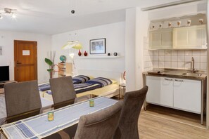 Espaço compacto com cama, mesa de jantar, cadeiras, cozinha e televisão.
