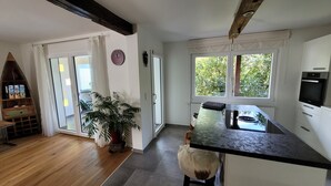 A modern kitchen with a wooden floor, a large window, and a built-in oven. - Apartment 'Schwarzwald-Traum' with Mountain View, Private Terrace and Wi-Fi (Haslach im Kinzigtal)
