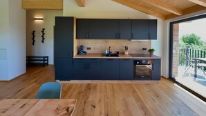 A modern kitchen with dark cabinets, a wooden countertop, and a dining area with a table and chairs. - Holiday Home 'Steinackerhof - 2' with Mountain View, Shared Garden and Wi-Fi (Dachsberg (Südschwarzwald))