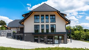 A modern two-story building with a flat roof, large windows, and a paved entrance area. - Holiday Home 'Steinackerhof - 2' with Mountain View, Shared Garden and Wi-Fi (Dachsberg (Südschwarzwald))