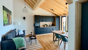 A modern interior with a wooden ceiling, a kitchen with dark cabinets, a dining area with a table and chairs, and a living area with a sofa and a lamp. - Holiday Home 'Steinackerhof - 2' with Mountain View, Shared Garden and Wi-Fi (Dachsberg (Südschwarzwald))