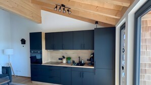 A modern kitchen with dark cabinets, a wooden ceiling, and a large window. - Holiday Apartment 'Spatzennest' with Mountain View, Balcony and Wi-Fi (Dachsberg (Südschwarzwald))