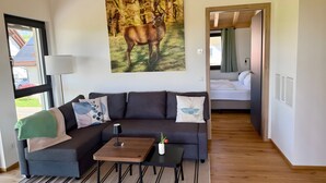 A modern room with a sofa, a coffee table, and a painting of a deer. - Holiday Apartment 'Schwalbennest' with Mountain View, Balcony and Wi-Fi (Dachsberg (Südschwarzwald))