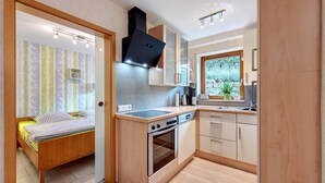 Una cocina compacta con horno empotrado, estufa y ventana con vistas a un jardín.