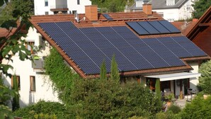 Un edificio residencial con paneles solares en el techo, rodeado de vegetación.