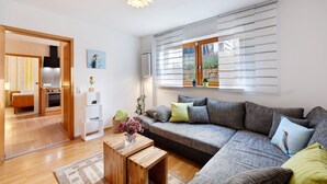 Una sala de estar moderna con un sofá, una mesa de centro y una cocina visible a través de una puerta abierta.