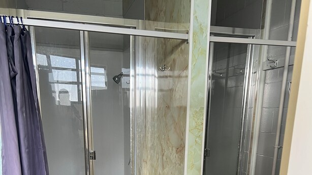 A glass-enclosed shower area with a marble wall, a towel rack, and a curtain. - Green Hayes Estate Rentals - R5 Magnolia House in quiet peaceful country setting (Temuka)