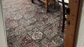 A room with a large wooden table and benches, a patterned rug, a window with curtains, and storage units against the wall. - Green Hayes Estate Rentals - R5 Magnolia House in quiet peaceful country setting (Temuka)