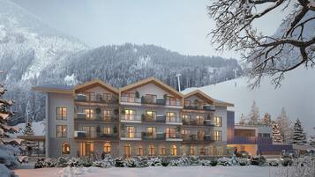 A multi-story hotel with balconies, large windows, and a view of snow-covered mountains.
