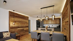 A modern kitchen with wooden accents, a dining area with a wooden table and chairs, and a living area with a sofa and a coffee table. - Apartment in Berwang with Ski-In/Ski-Out (Berwang)