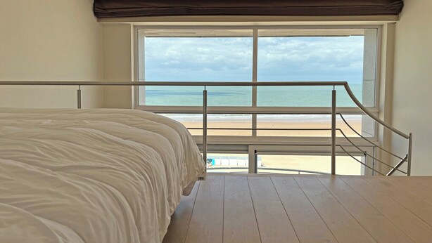 Un dormitorio con un ventanal grande que da a la playa.