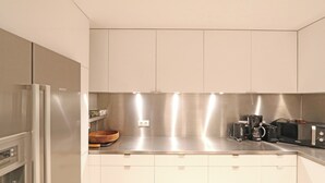 Een moderne keuken met witte kasten, roestvrijstalen apparatuur en een koffiezetapparaat.