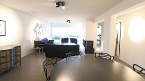 Een moderne woonkamer met een eettafel, bank en televisie.